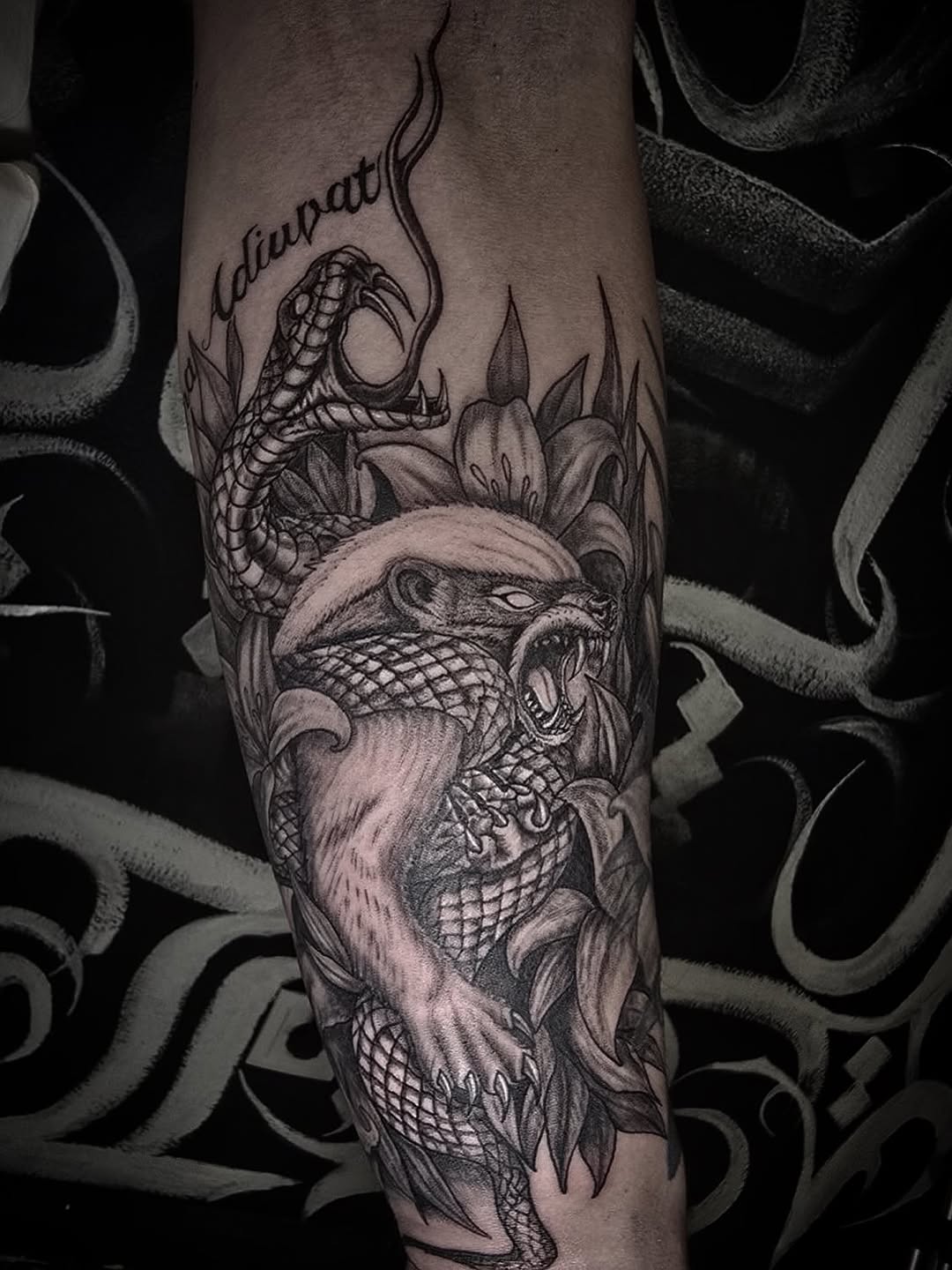 Tatuagem blackwork no antebraço — texugo-do-mel e serpente, trabalho Outcast